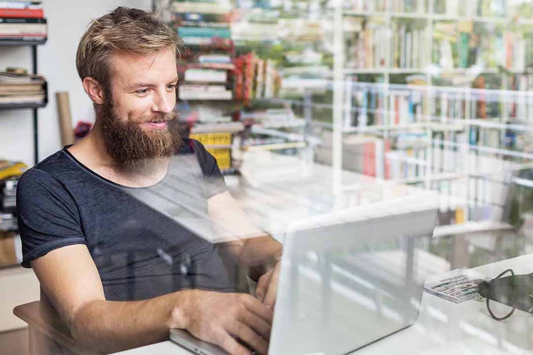 Baertiger Mann im Büro arbeitet an einem Laptop