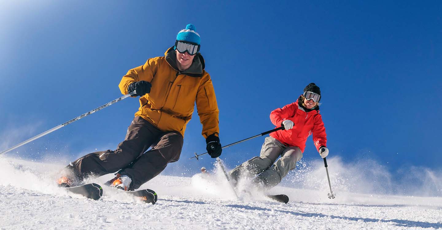 Skifahren: 2 Skifahrer auf der Piste