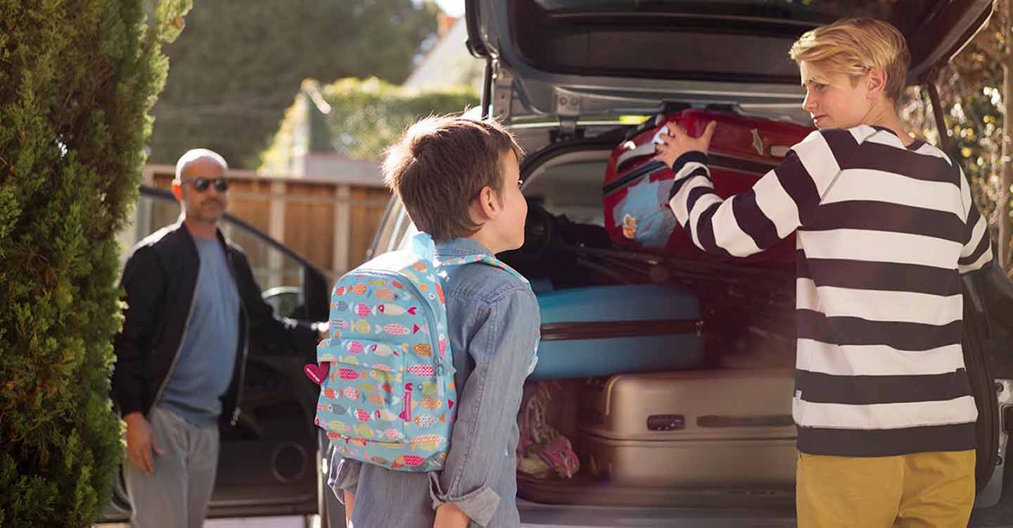 Familie packt Koffer in den Kofferraum