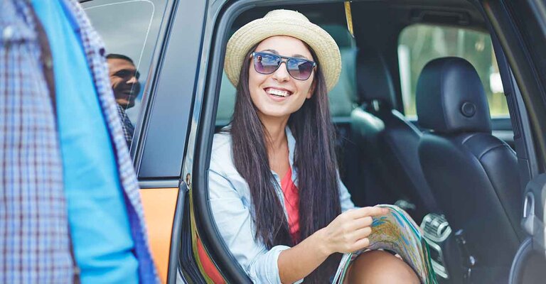 Frau mit Sonnenbrille sitzt in der geöffneten Autotür