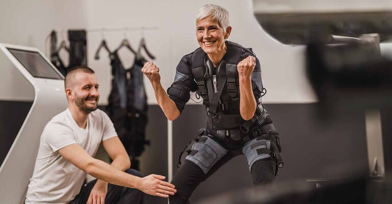 Frau trainiert in der Hocke mit einem Trainer die Muskulatur