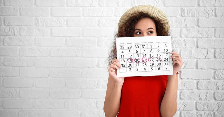 Junge Frau mit Kalender vor Ziegelwand