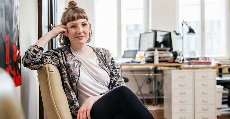 Junge Frau auf einem Stuhl schaut in die Kamera