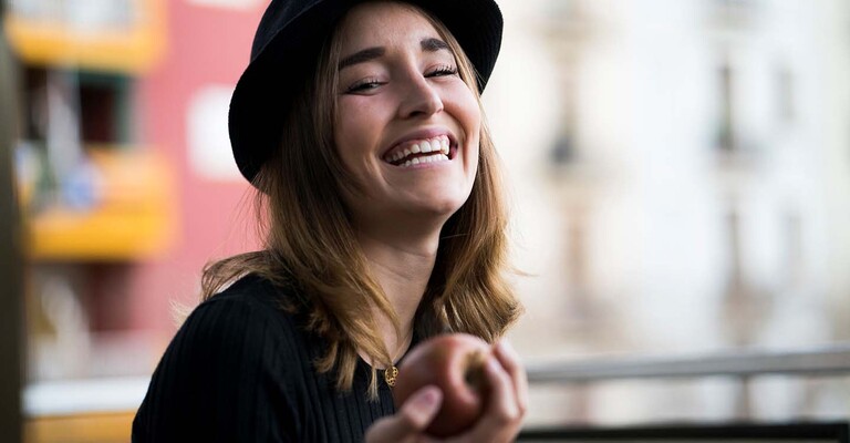 Lachende Frau mit Apfel in der Hand