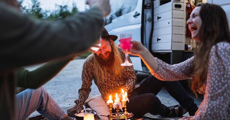 Personen sitzen beim Picknick und prosten sich zu