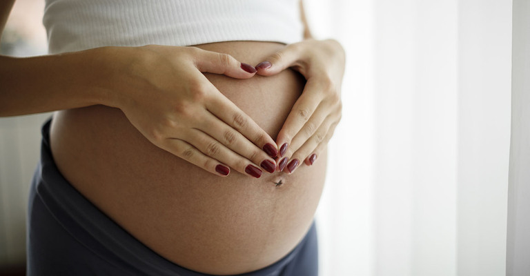 Schwangere Frau hält Ihre Hände auf ihren Bauch