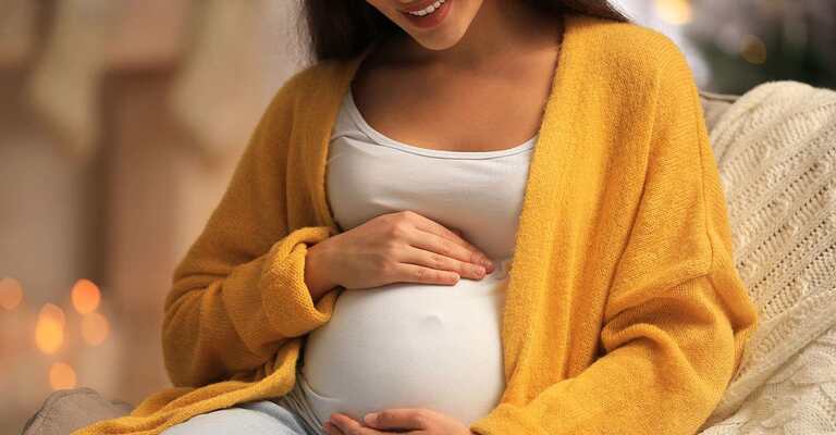 Eine Schwangere Frau die liebevoll über ihren Bauch streichelt.