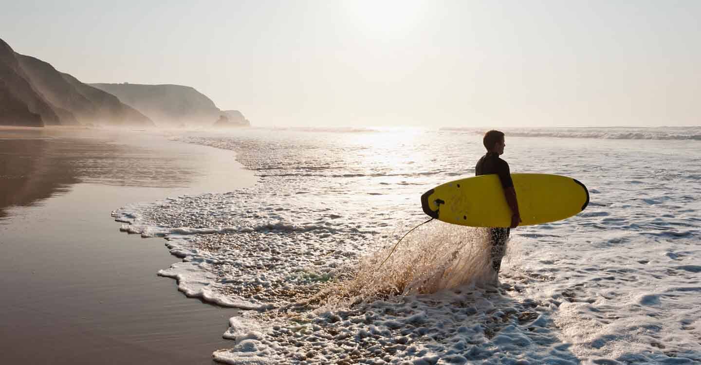 Surfer mit Surfboard in der Meeresbrandung