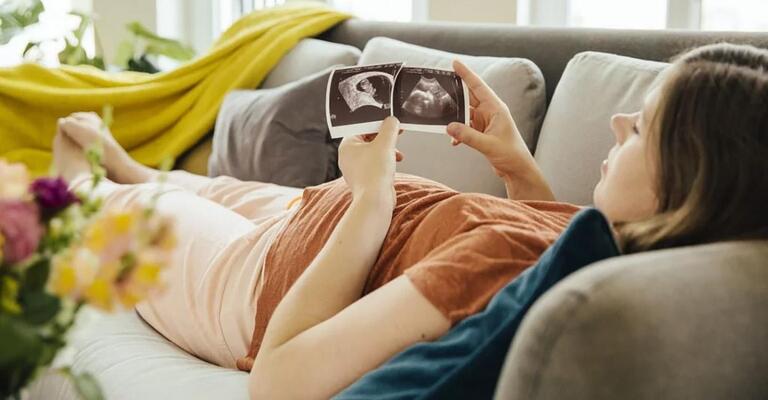 Eine Frau sitzt auf einem Sofa und schaut auf Ihr Smartphone